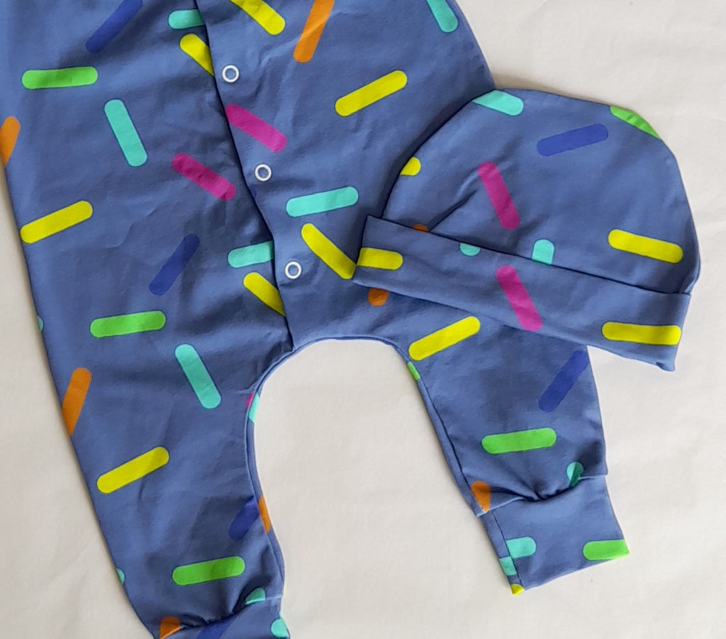 Confetti Romper and Hat Set by Little Loves Cornwall, slate blue with yellow, lime, teal, pink and orange sprinkles, flat lay with hat