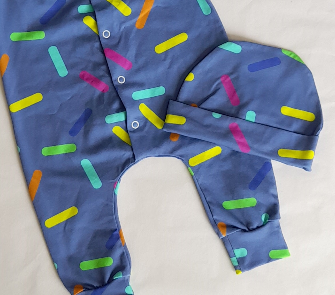 Confetti Romper and Hat Set by Little Loves Cornwall, slate blue with yellow, lime, teal, pink and orange sprinkles, flat lay with hat